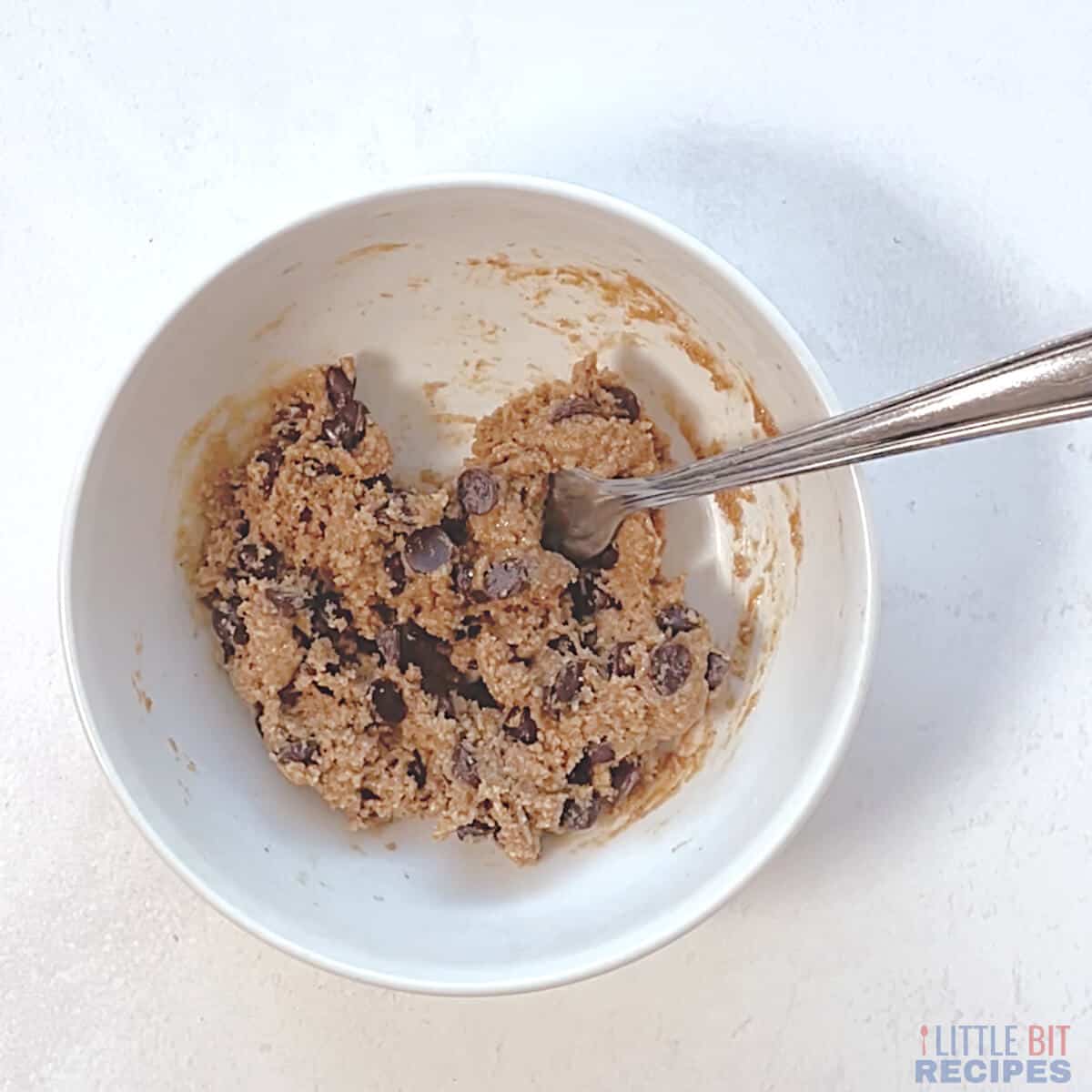 chocolate chip cookie dough in small white bowl with fork.