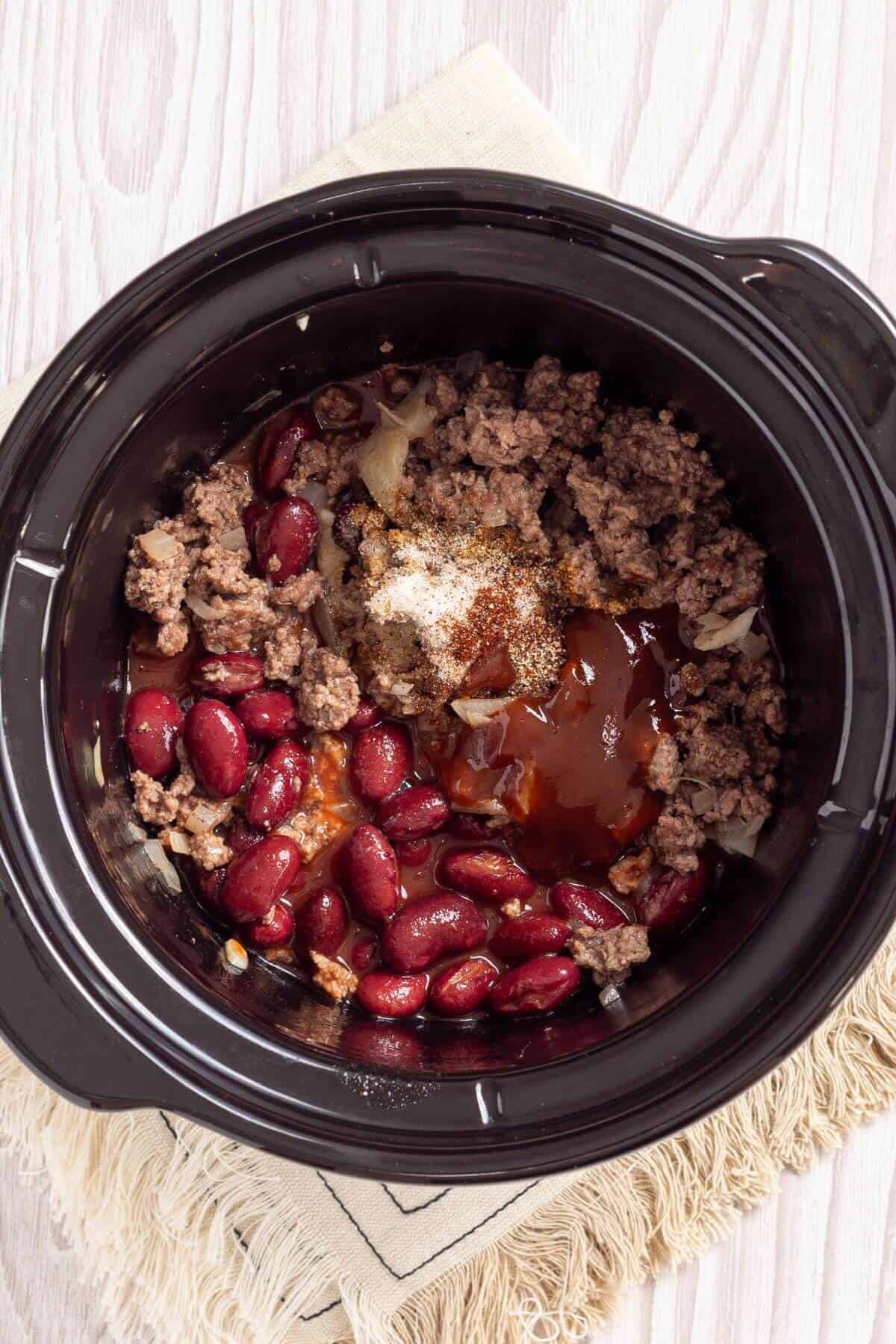 A crock pot with beans and meat.
