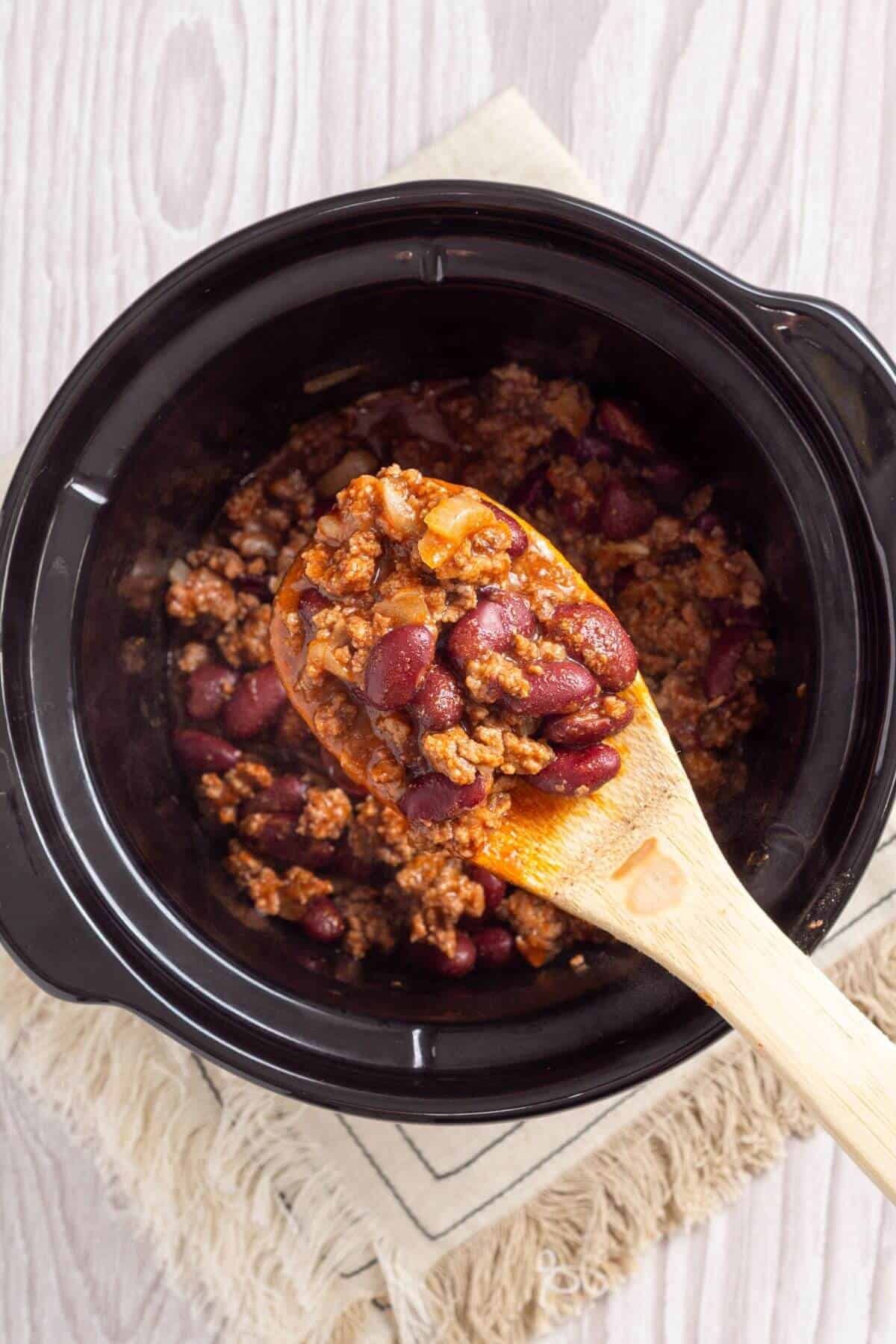 Chili for two slow cooked with a wooden spoon.
