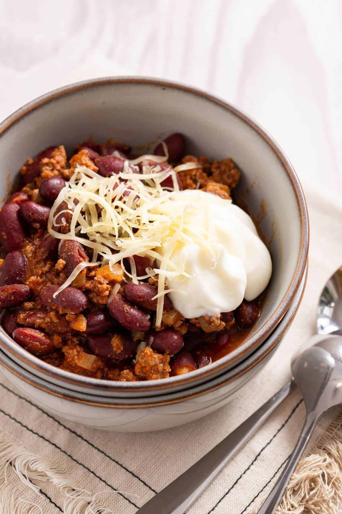 A bowl of chili for two, served with cheese and sour cream.