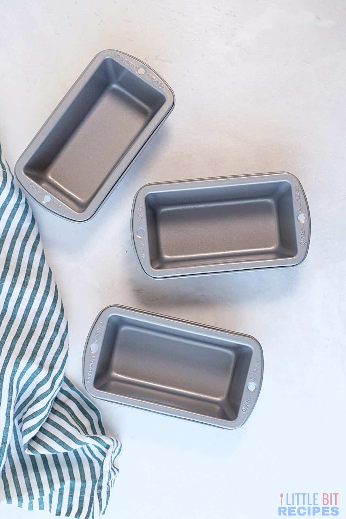 metal bread loaf pans with striped towel.