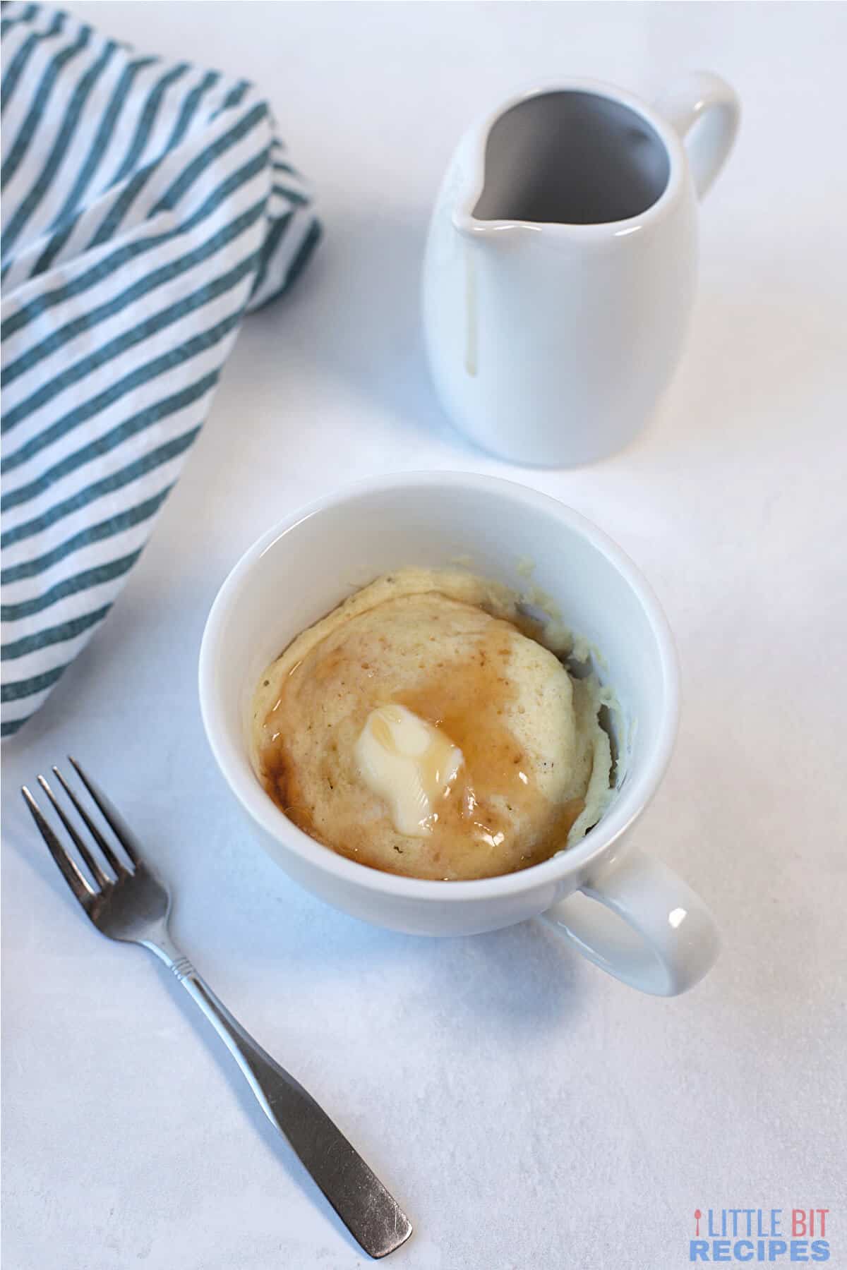 serving pancake in mug with butter and maple syrup.