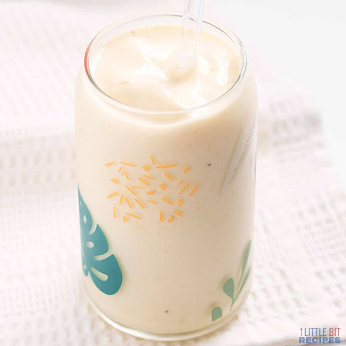 pineapple banana smoothie in glass with straw.