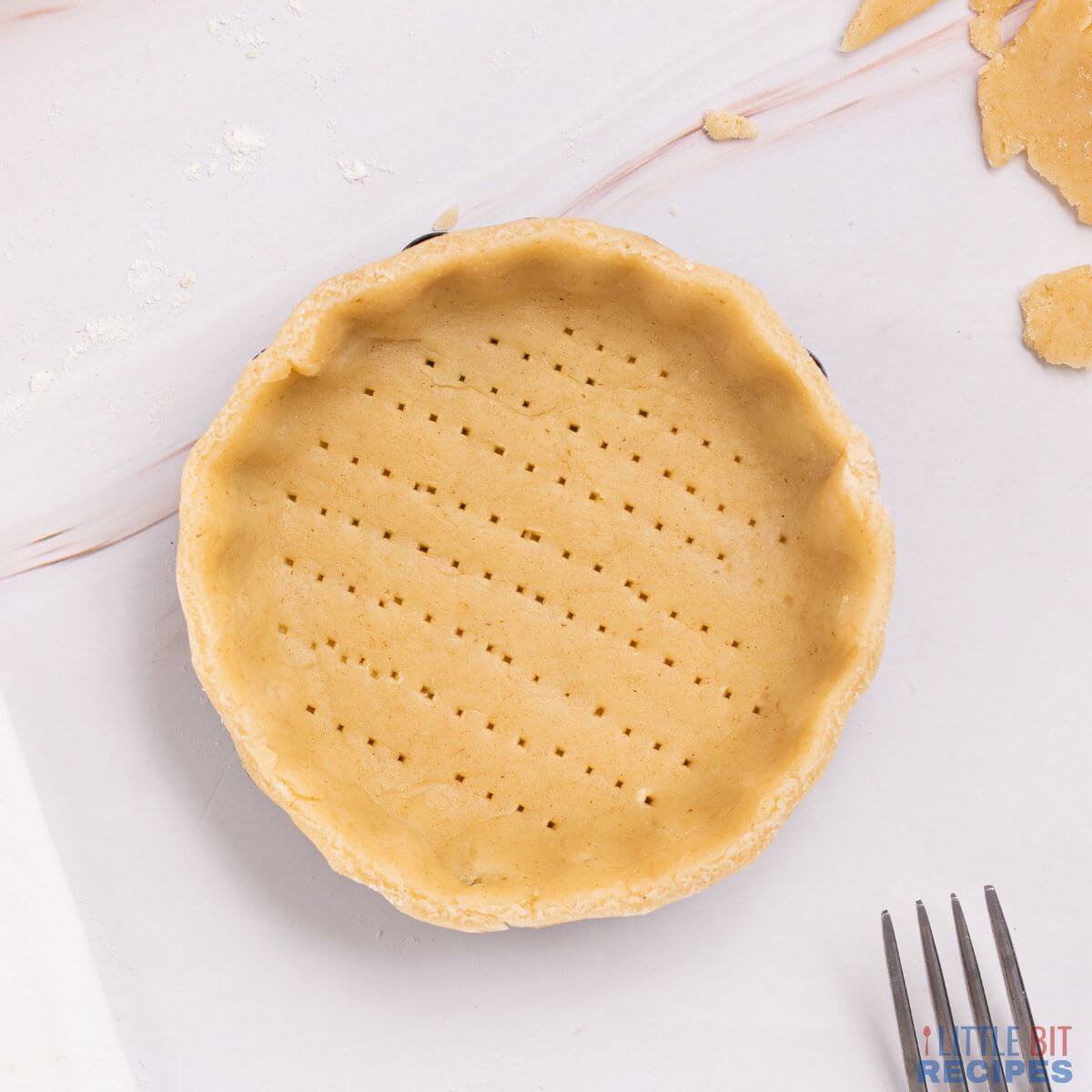 unbaked pie crust with fork piercing at base.