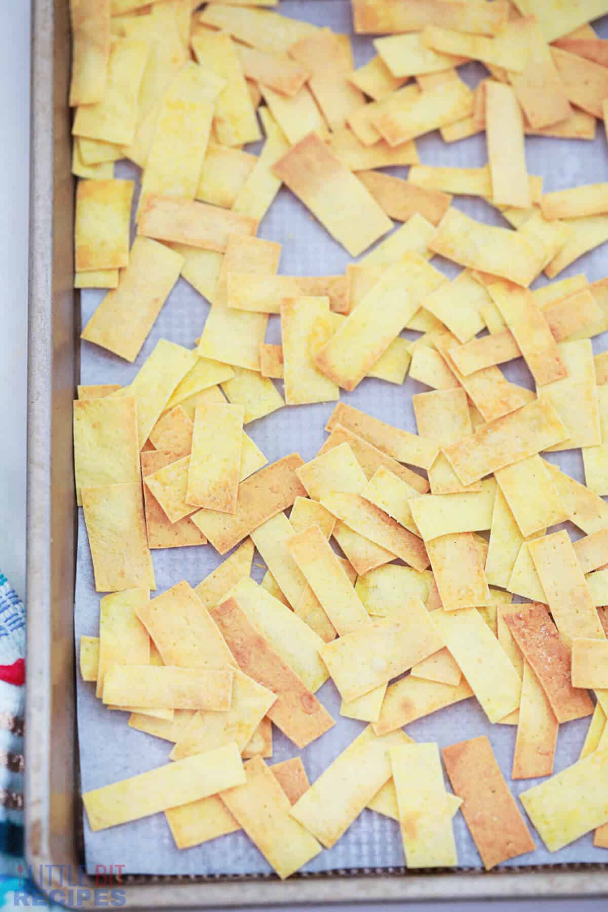 baked tortilla strips on parchment paper lined baking sheet.