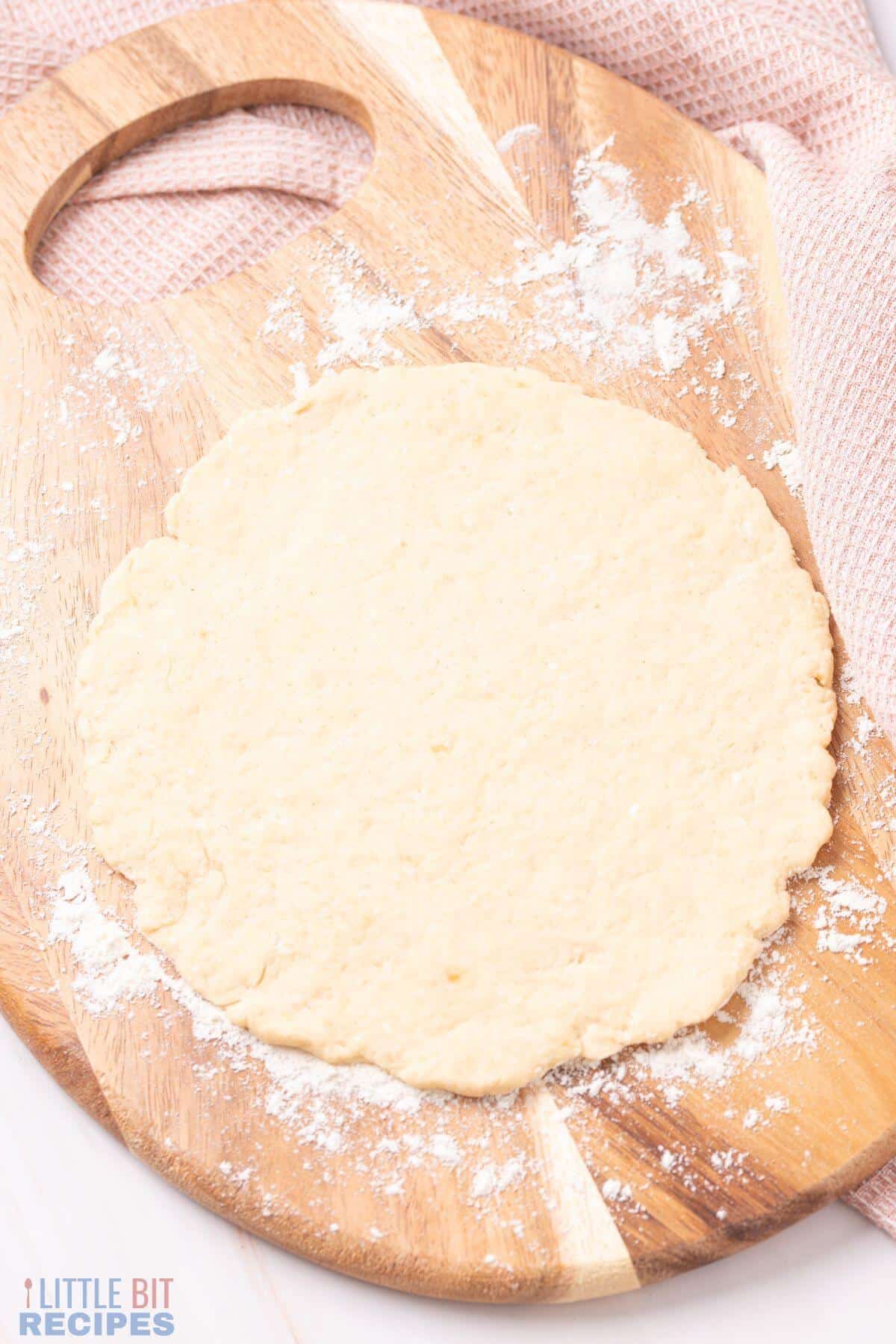 pizza dough rolled out on floured board.