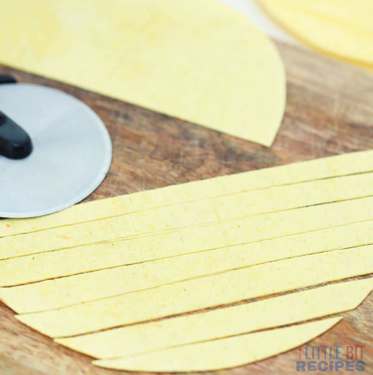 cutting tortillas in long strips with pizza slicer.