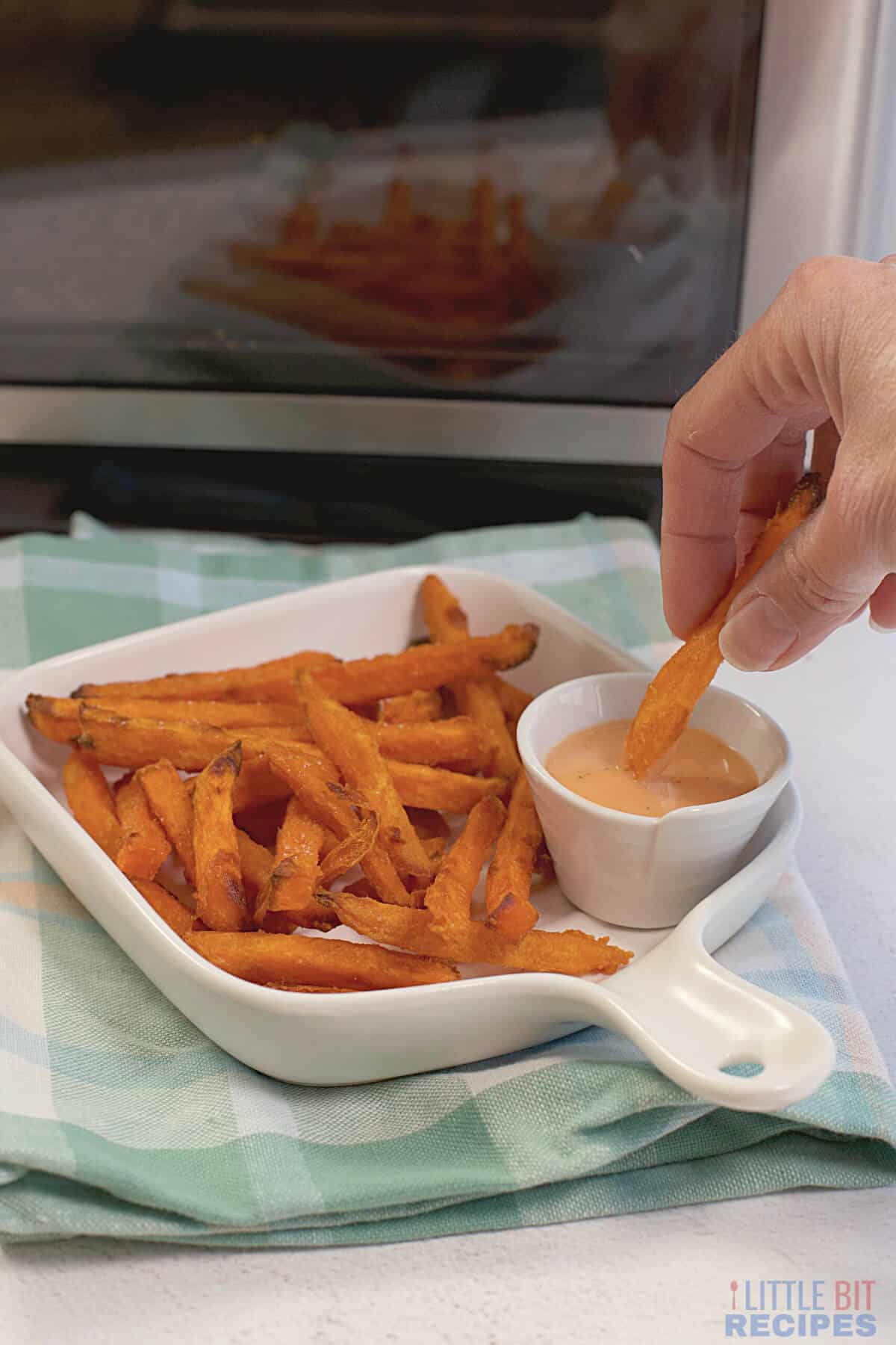 dipping sweet potato fry in sauce.