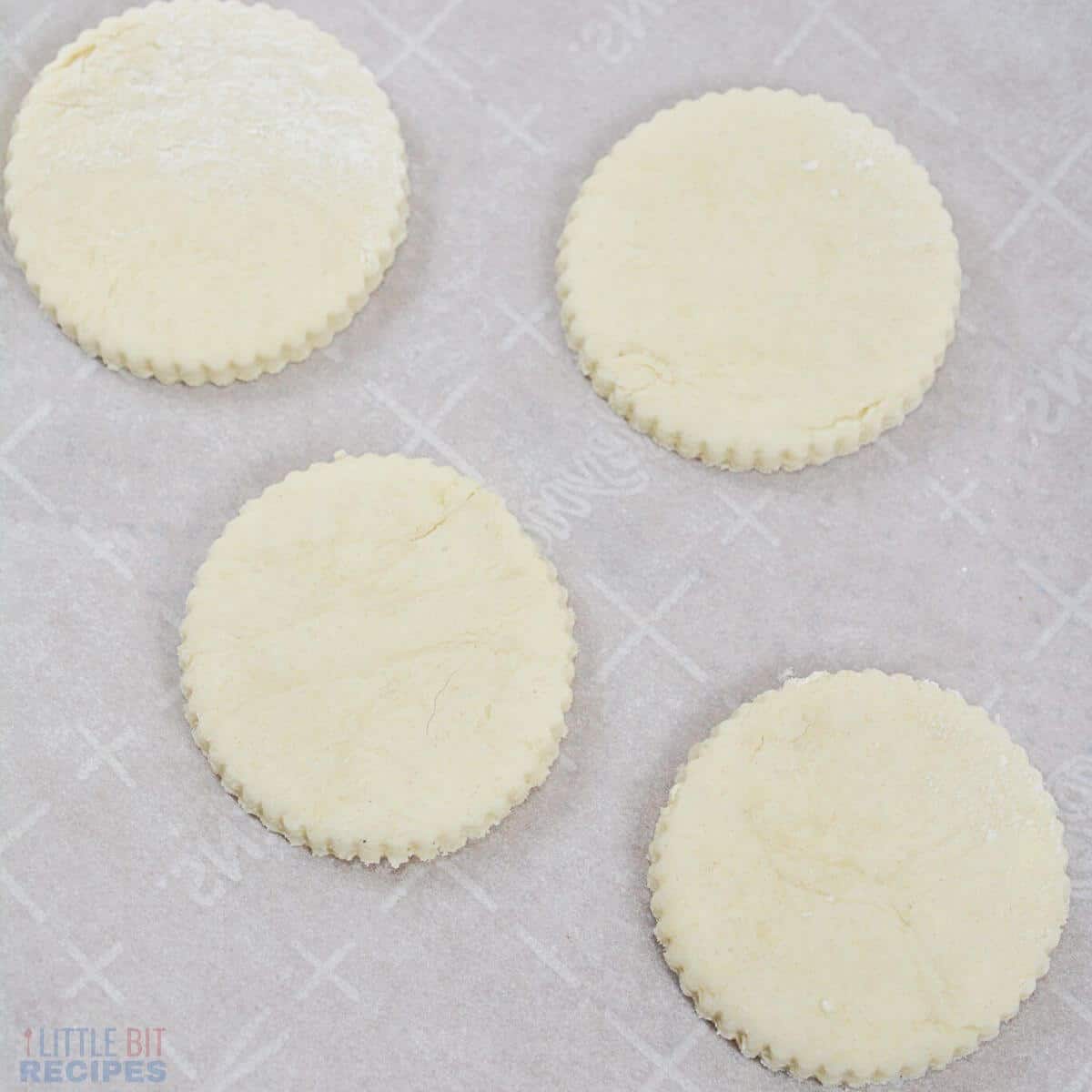 dough cut into biscuit circles on parchment lined baking sheet.