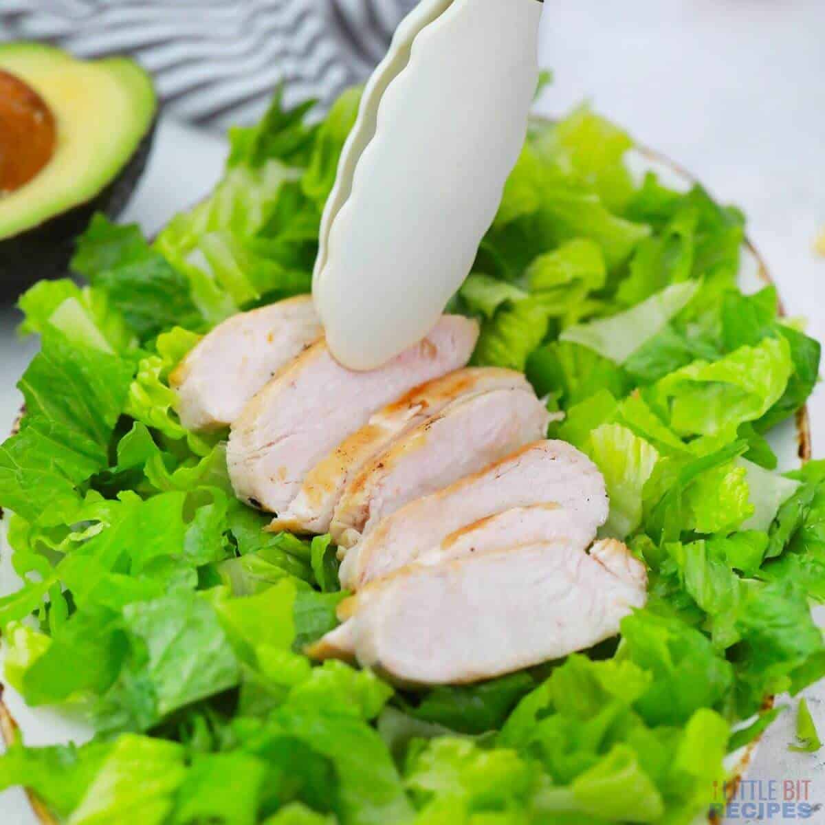 topping lettuce with chicken slices.
