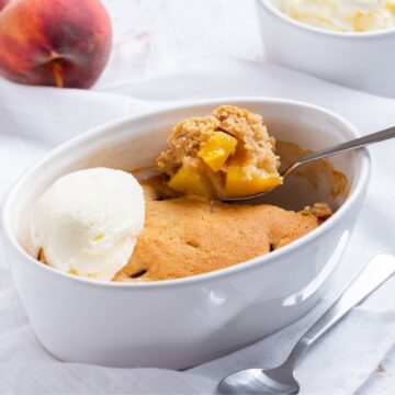 Peach cobbler with ice cream and peaches for one.