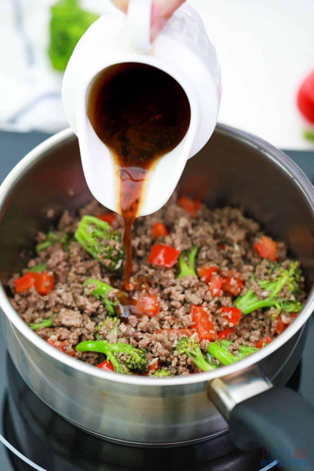 pouring sauce over beef and broccoli mixture in pot.