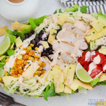 santa fe salad on oval plate with dressing and striped napkin..
