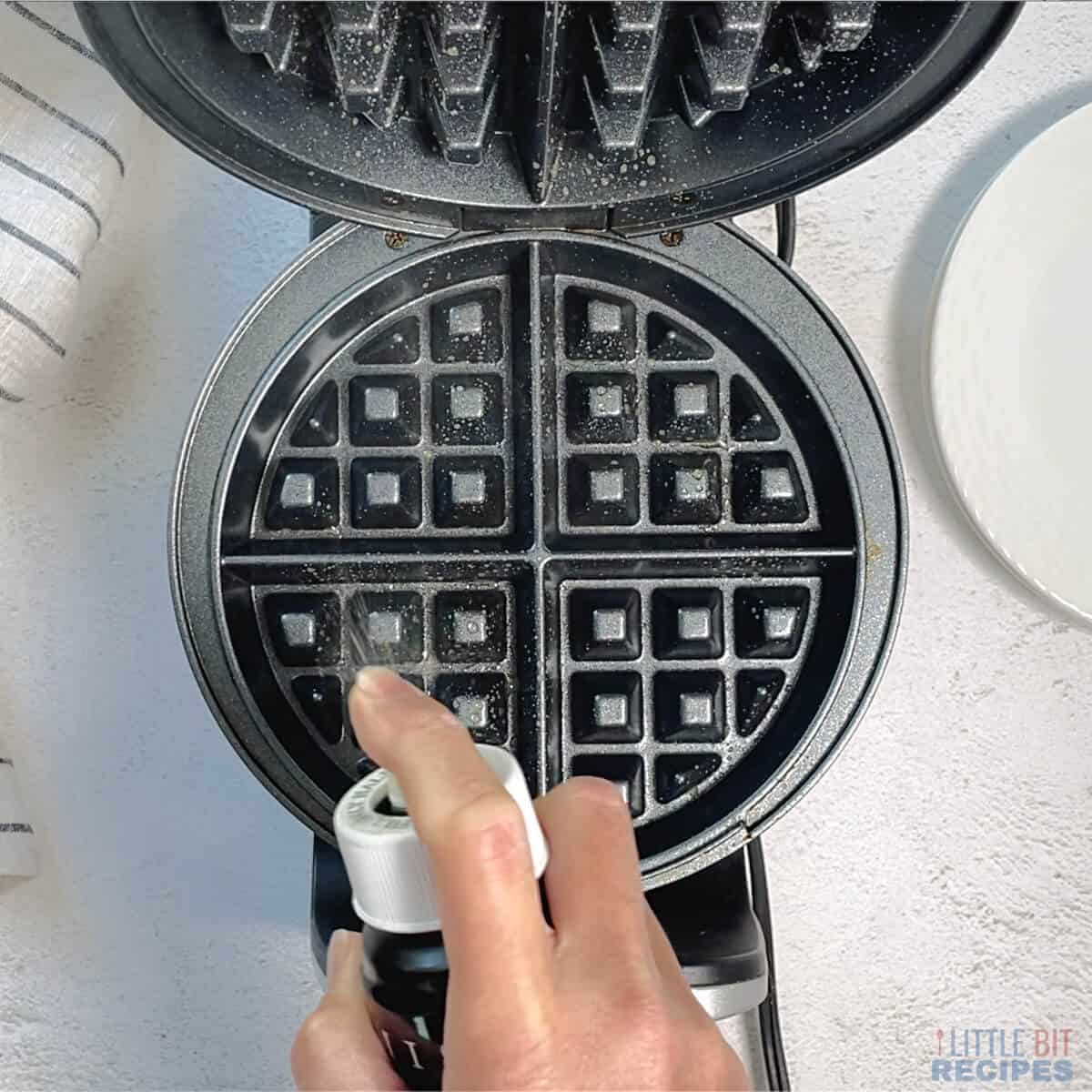 spraying waffle iron with oil.