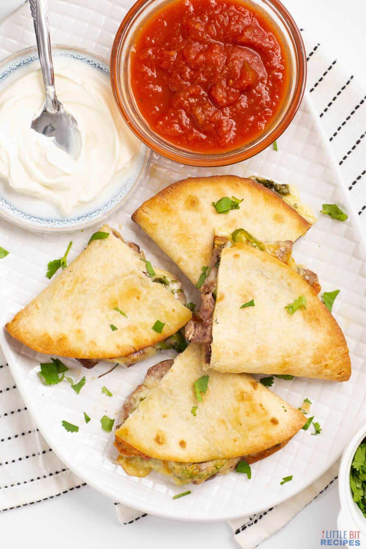 beef steak quesadillas with salsa and sour cream.