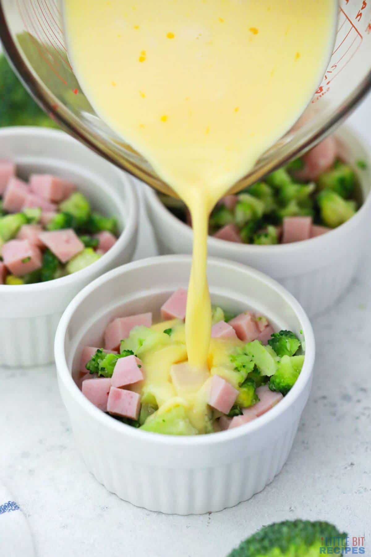 pouring egg mixture over ham and broccoli.