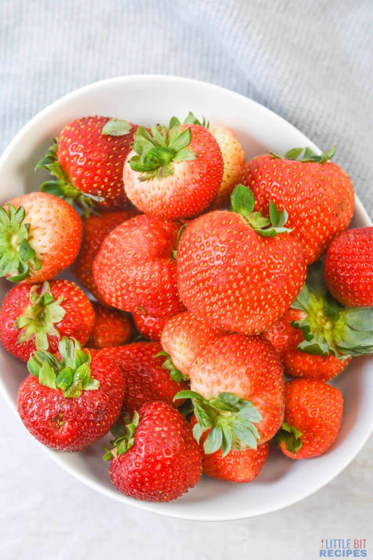 white bowl filled with strawberries.