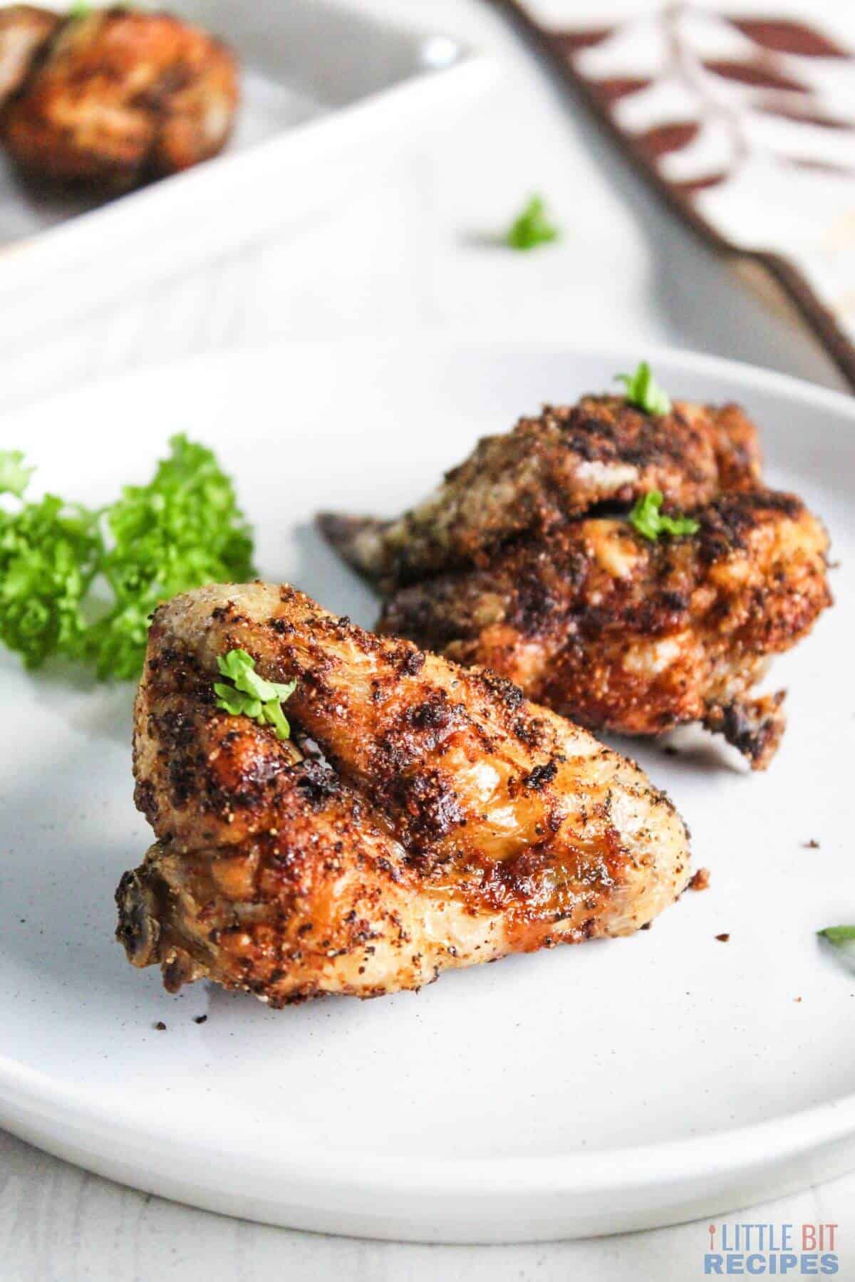 Air fryer cooked chicken wings on serving plate.