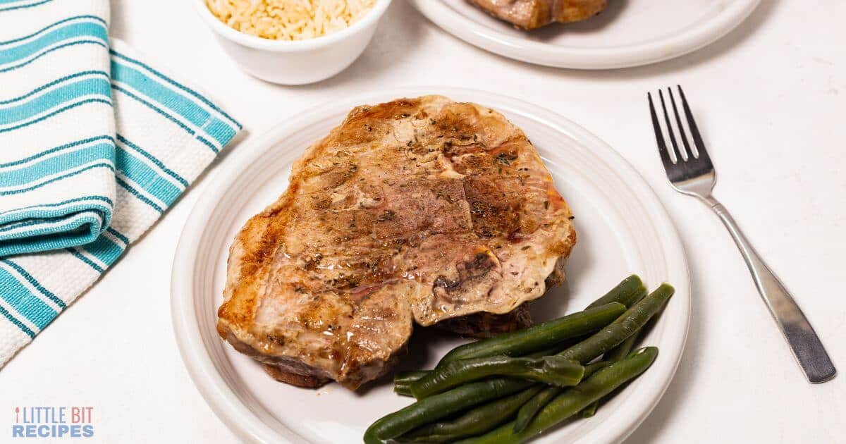 Oven baked pork steak on plate with green beans.