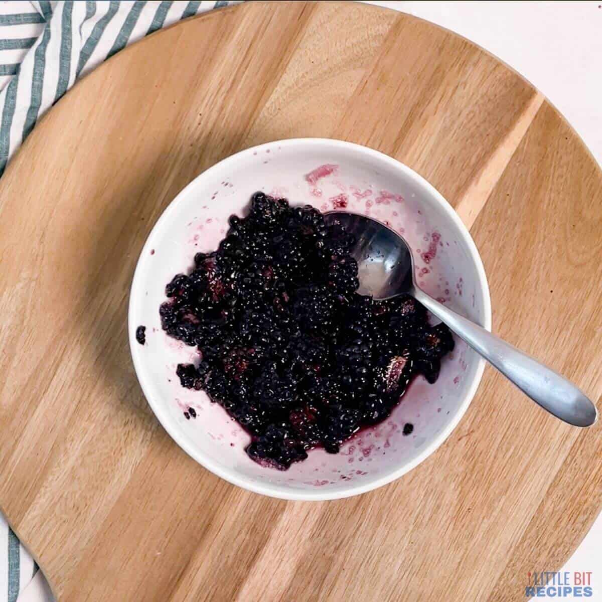 mashed sweetened blackberries in bowl with spoon.