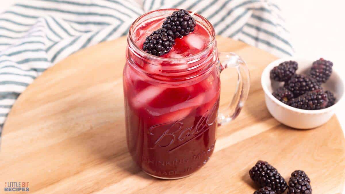 Mason jar glass of blackberry tea with blackberries.