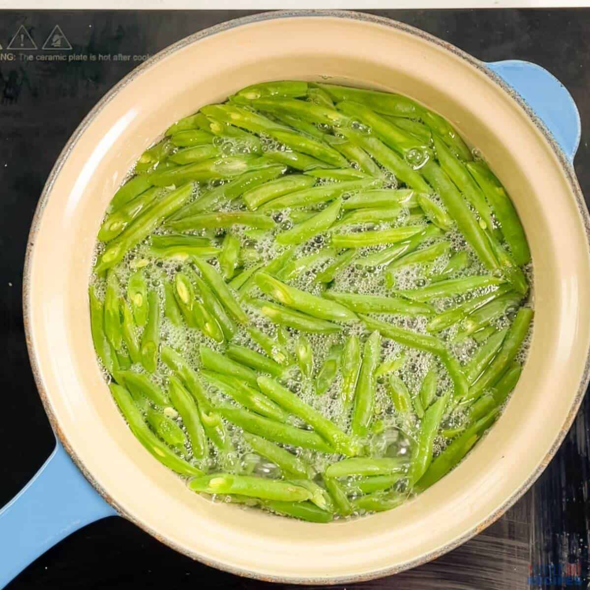 boiling cut green beans in saucepan.