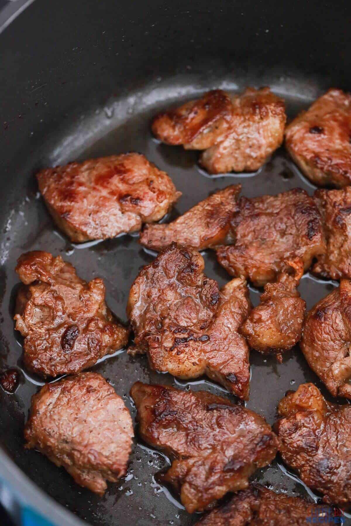 browned meat in cast iron pan.