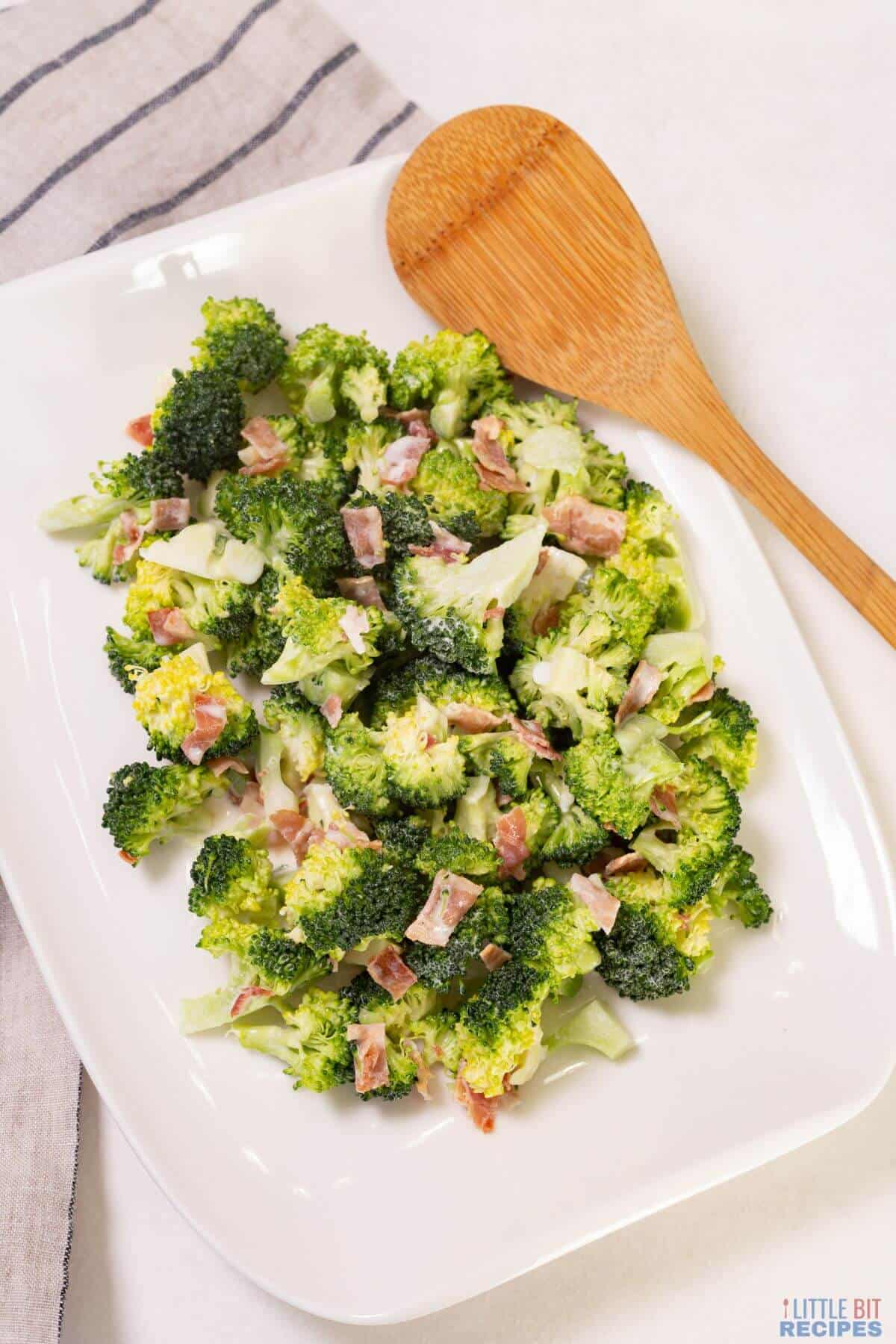 broccoli salad on platter with wooden spoon.