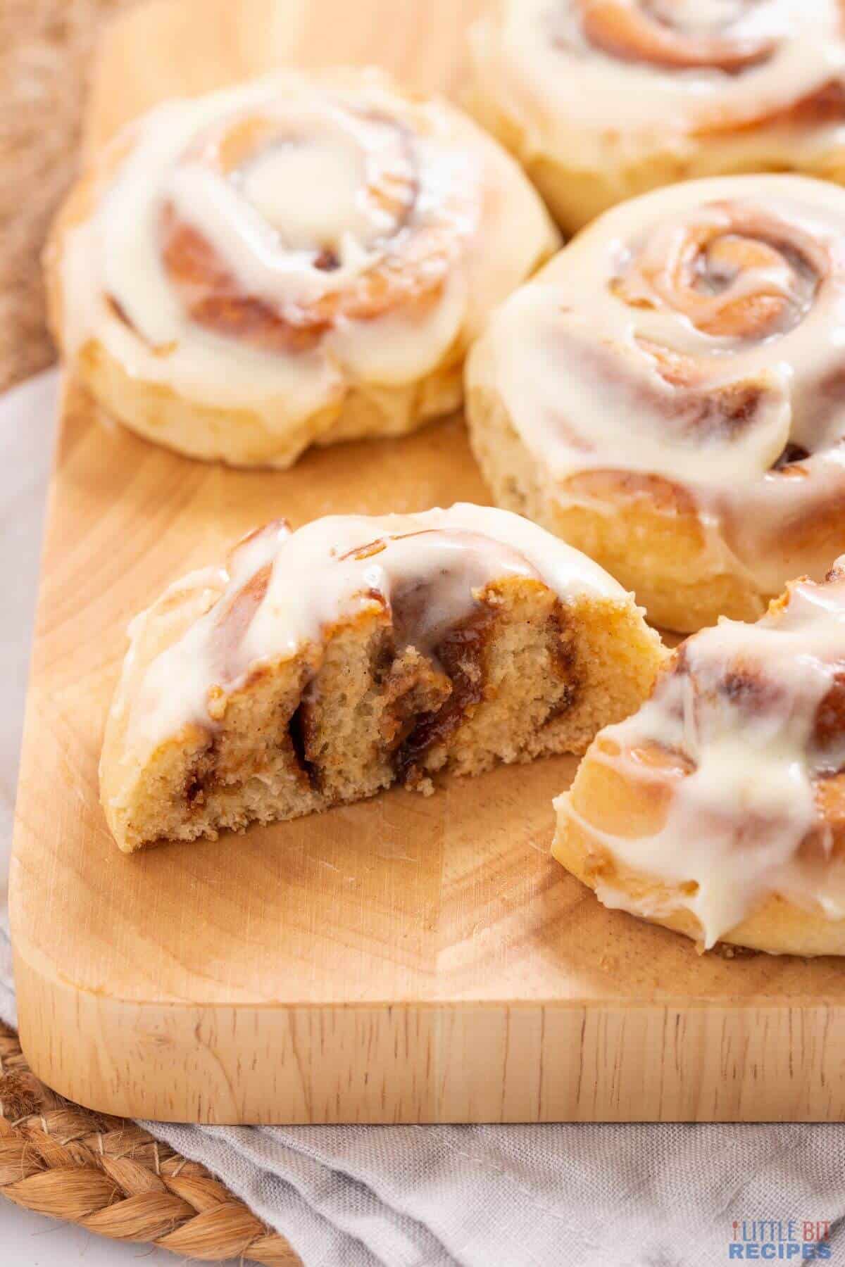 cinnamon rolls on board with one sliced in half.