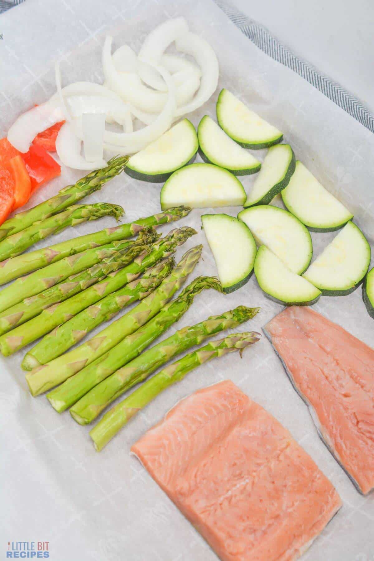 salmon and vegetables on lined sheet pan.