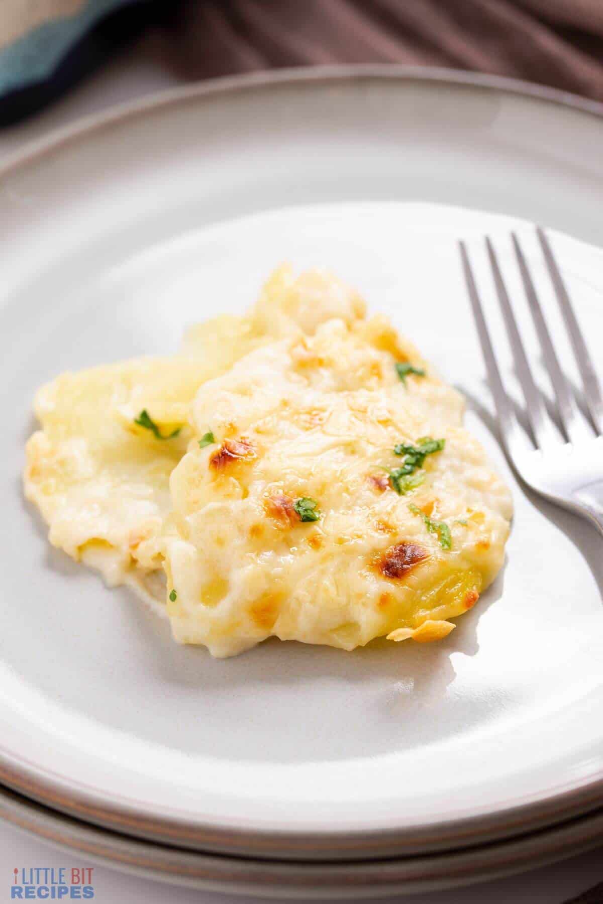 serving of scalloped potatoes on plate with fork.