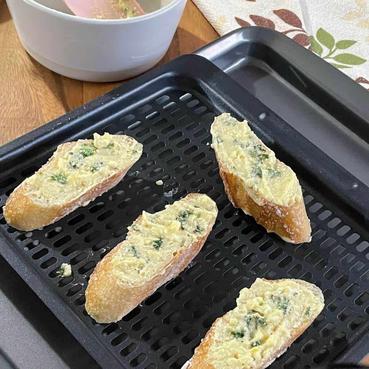 buttered garlic bread slices on air fryer tray.