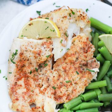 butter fish on plate with lemon slice and green beans.