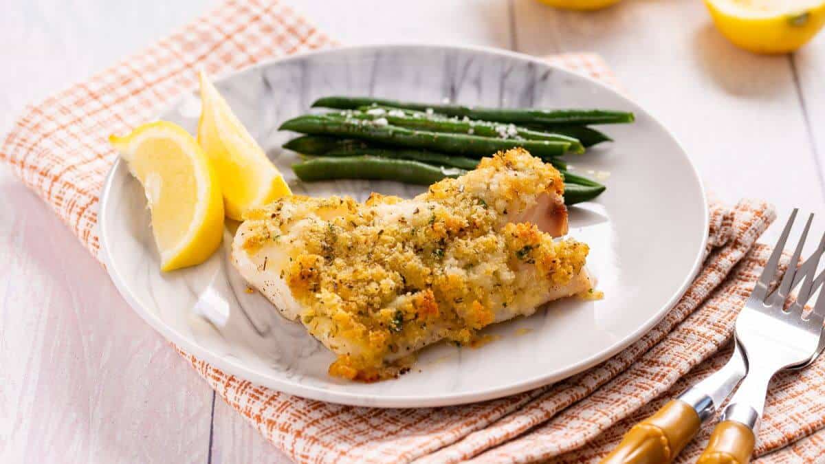 Panko-crusted cod fish on a plate with green beans.