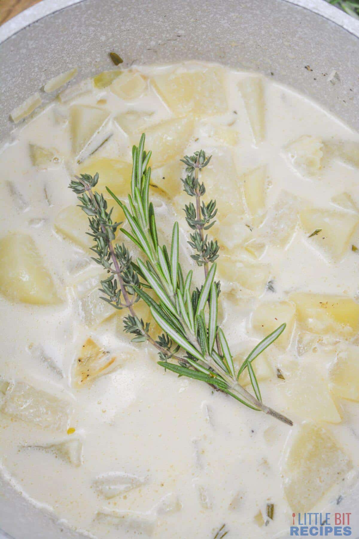 potato soup in pot with fresh herb garnish.