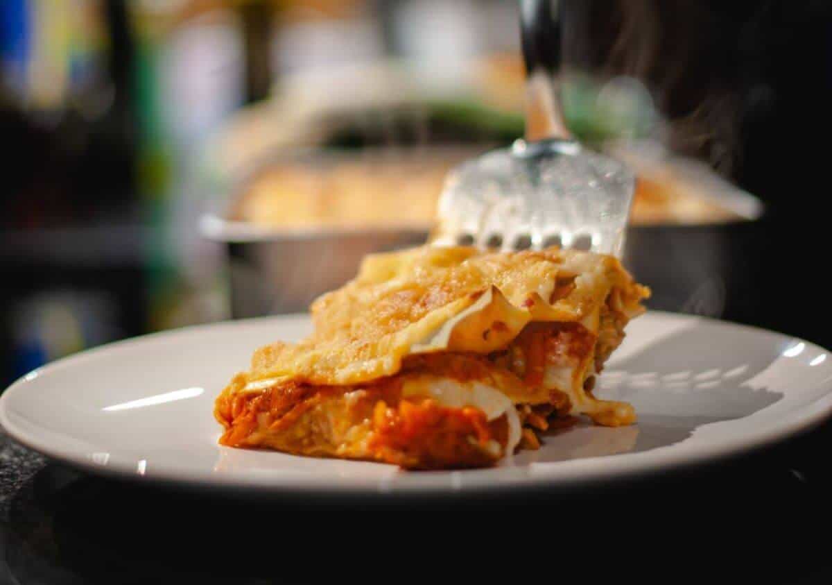 slice of lasagna being placed on serving plate.
