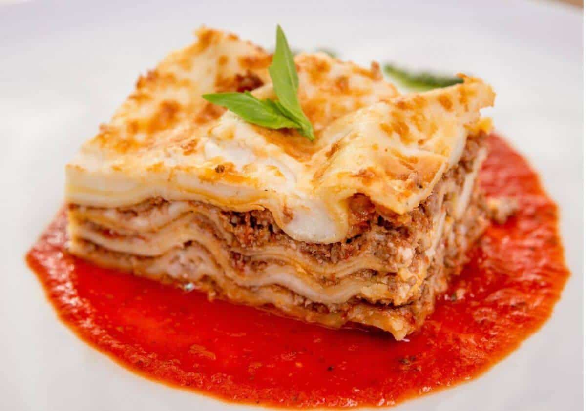 slice of lasagna on place with extra sauce.