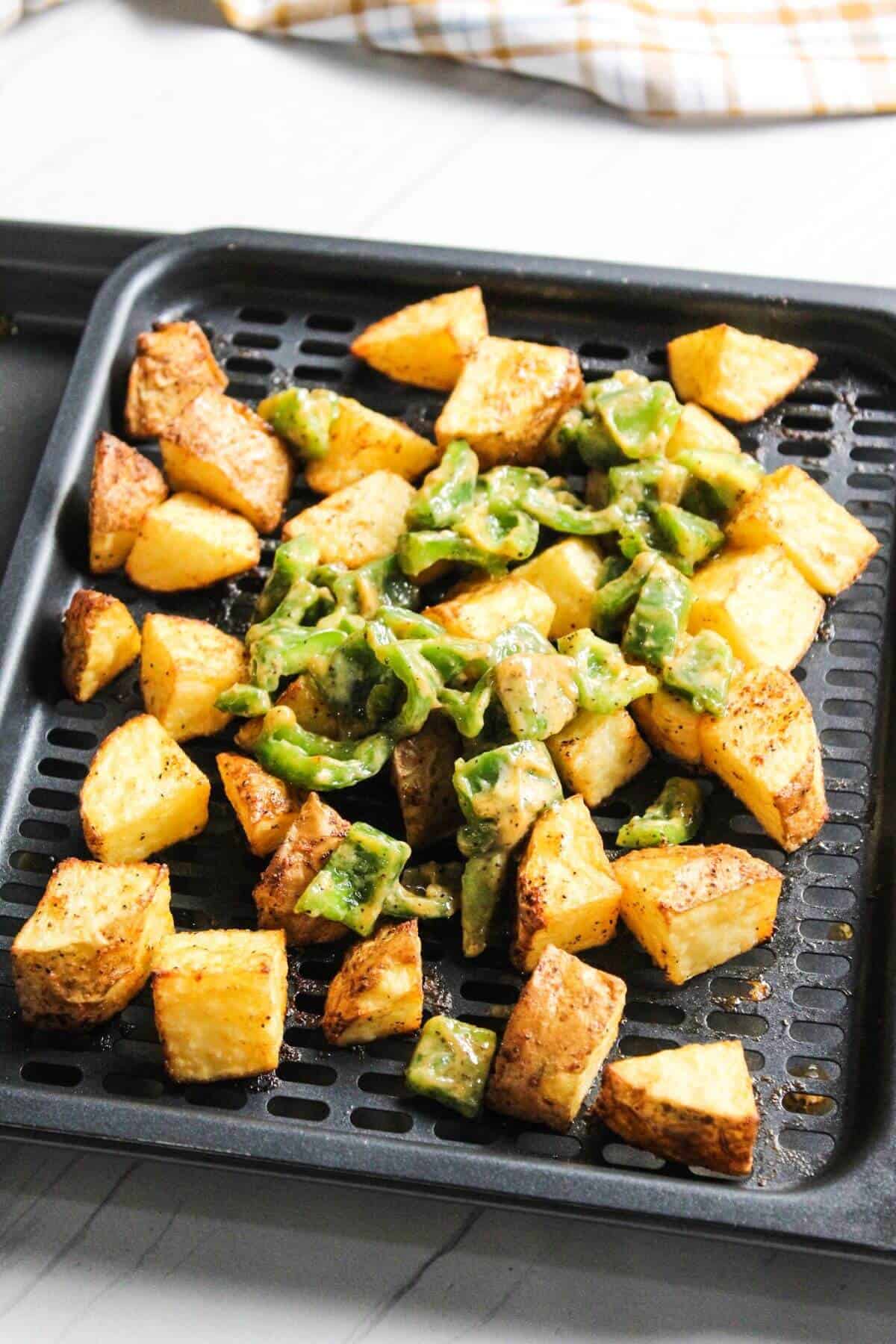 Green bell pepper added to potato chunks on tray.