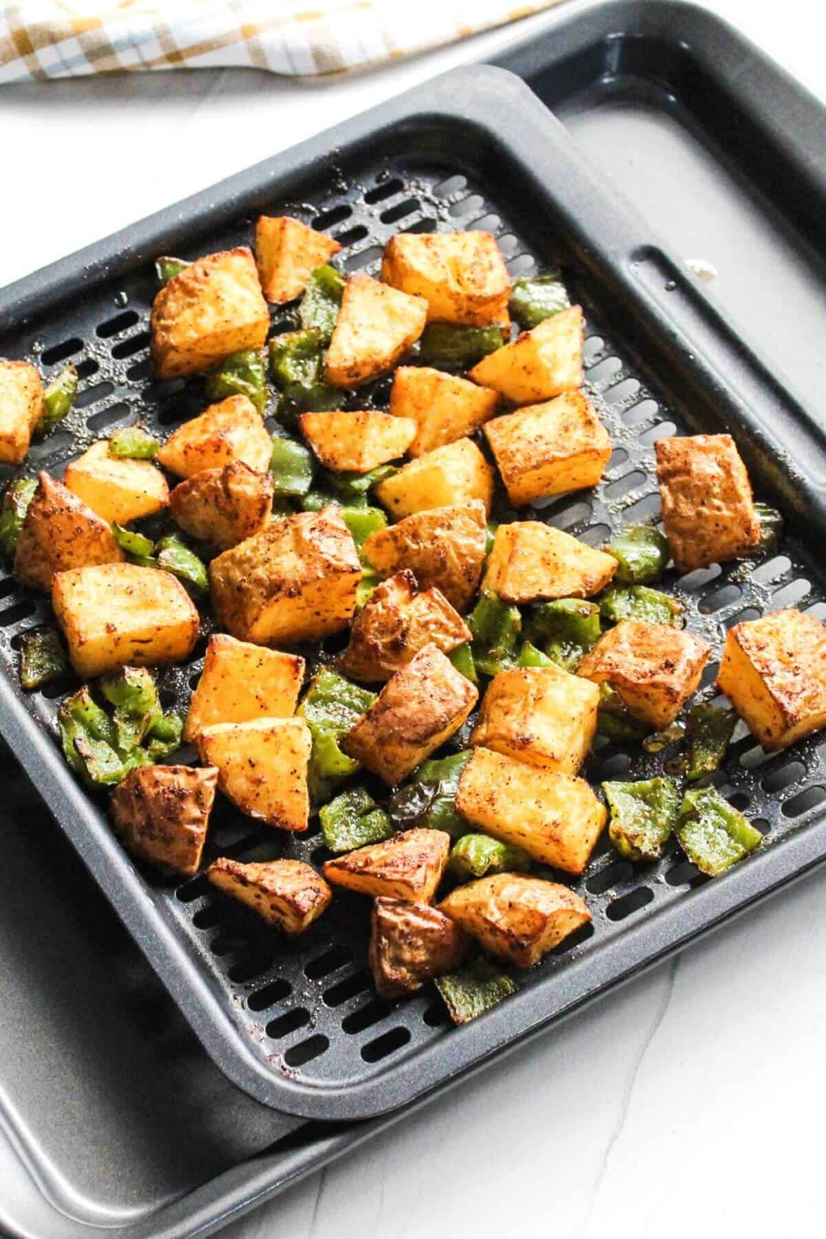 Cooked home fries in air fryer tray.