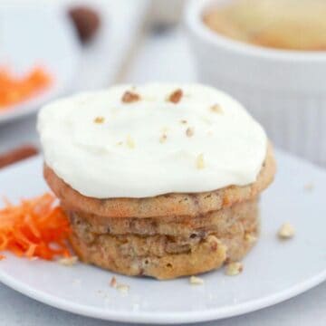 Carrot cake in mug shown frosted on plate.