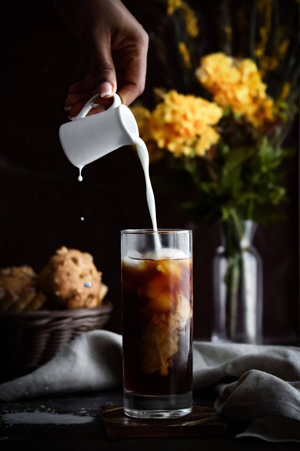 Pouring cream into a glass of cold brew coffee.