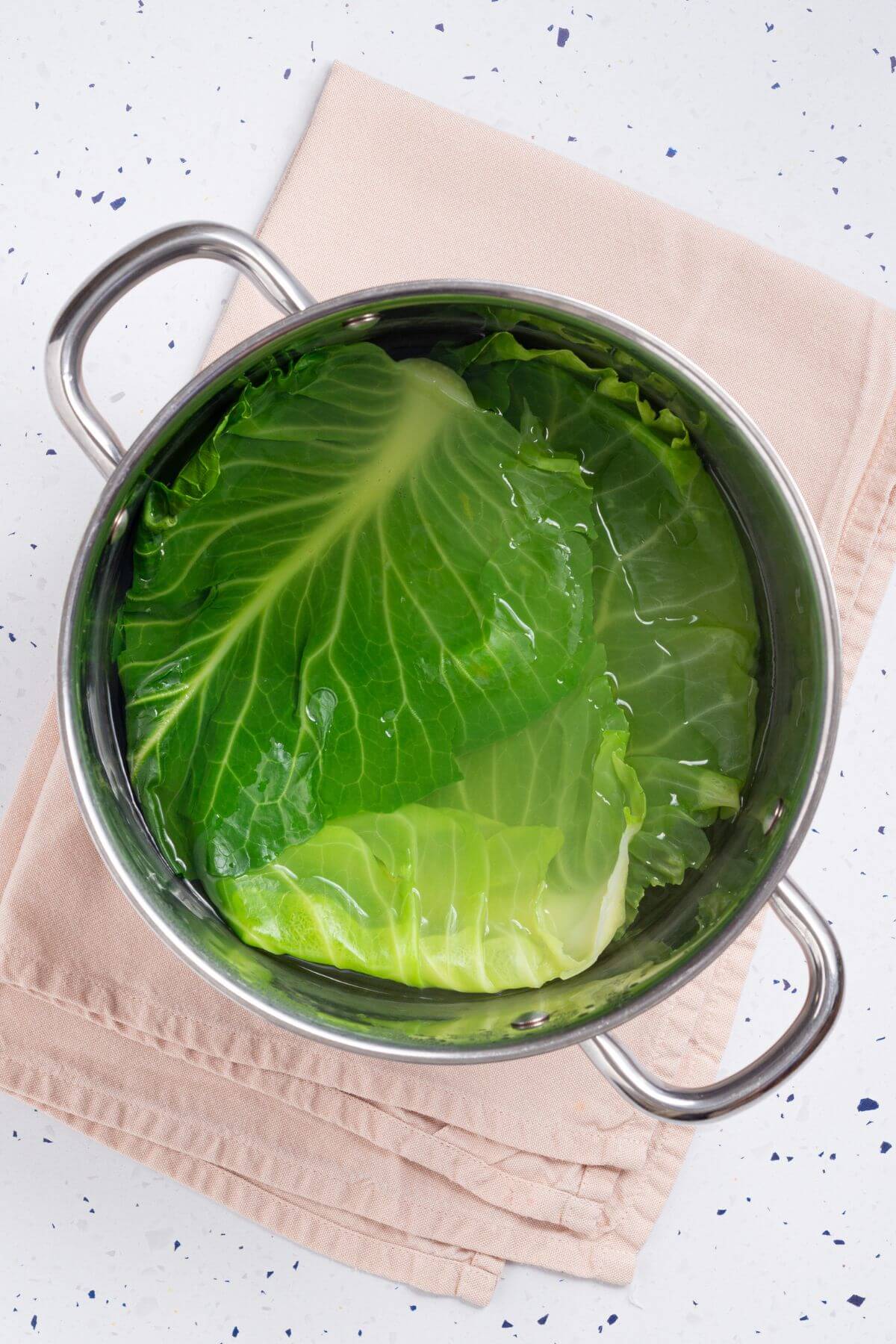 Boiling cabbage leaves in large pan.