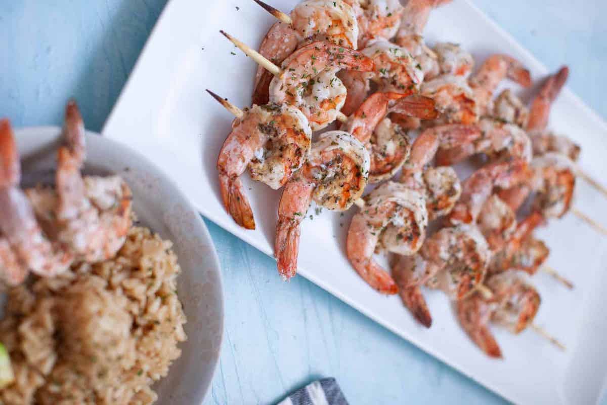 Grilled shrimp skewers on square platter.