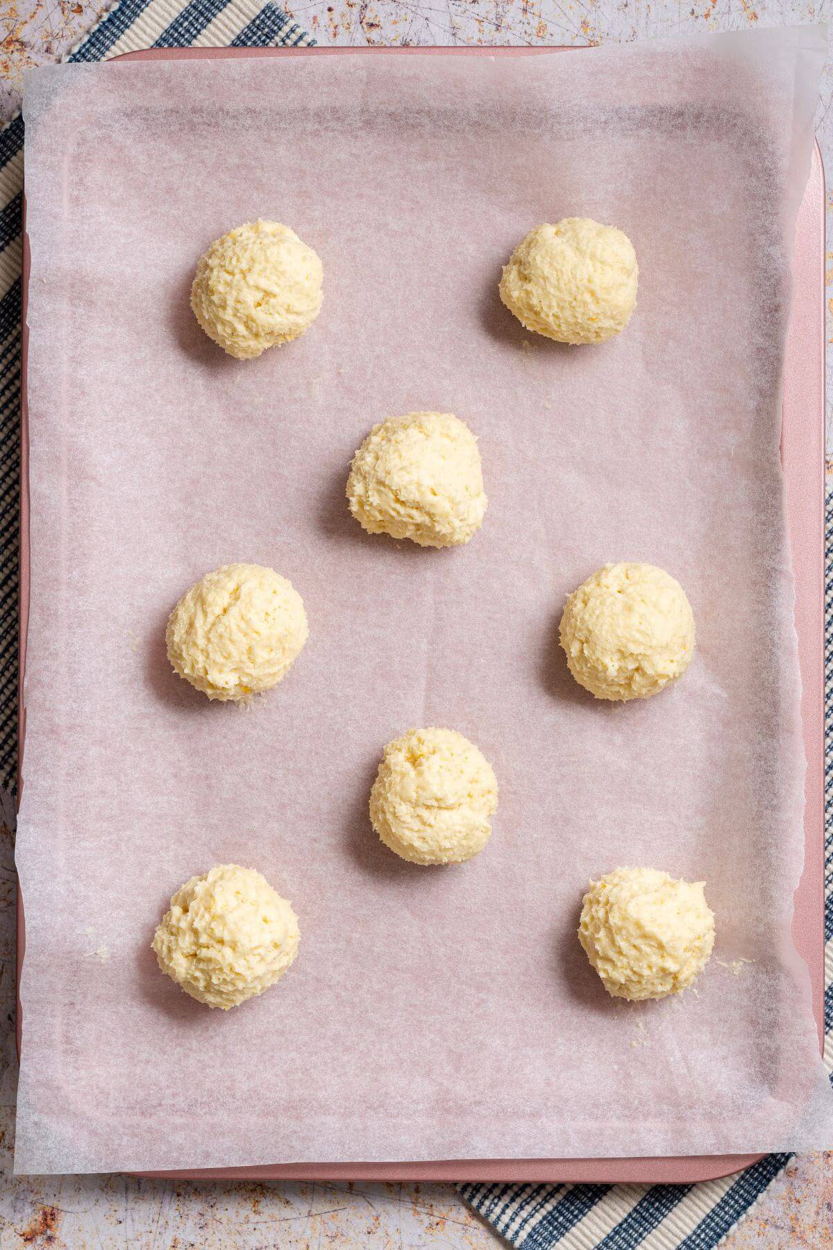 Cookie dough balls on lined baking sheet.