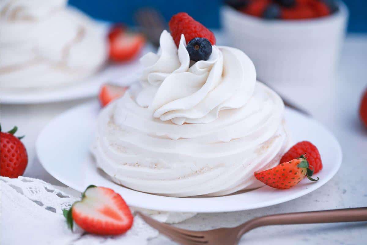 Mini pavlova on white plate with berries.