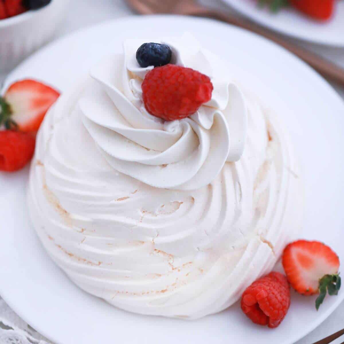 Mini pavlova nest with whipped cream and berries.