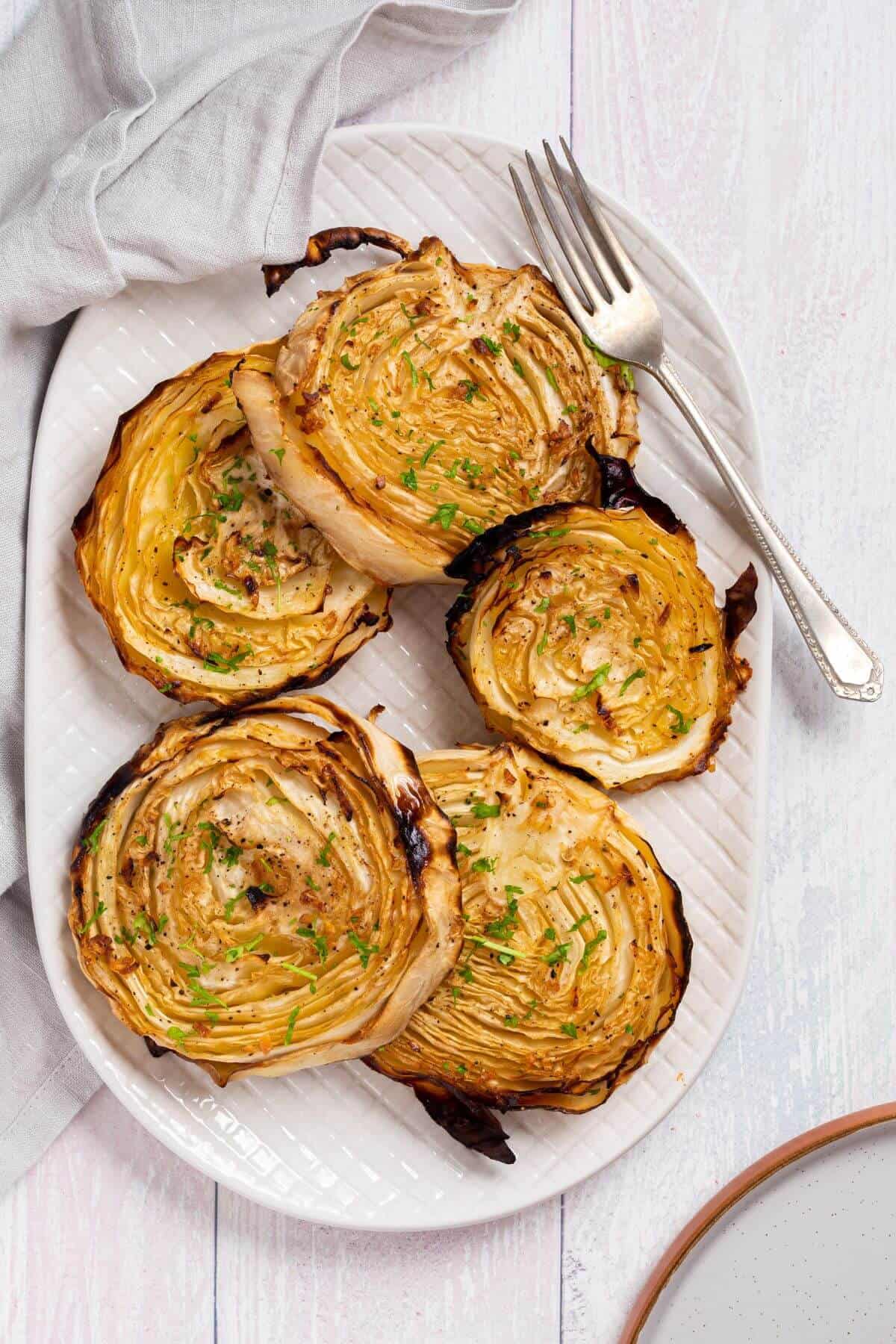 Roasted cabbage steaks on platter with fork.