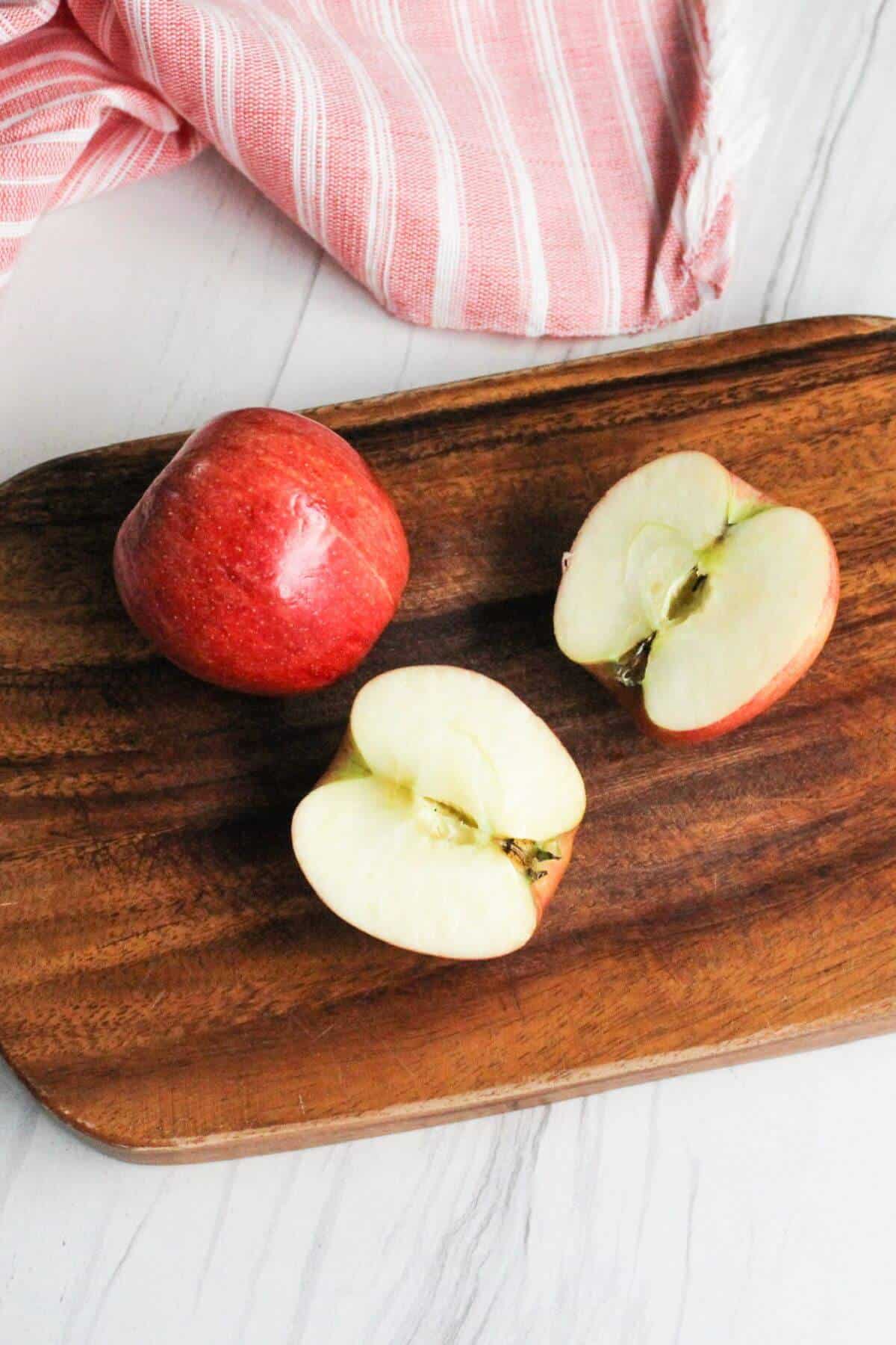 Cut gala apple on wood cutting board.