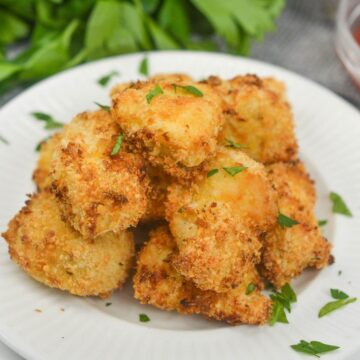 Air fryer chicken nuggets piled on white plate.