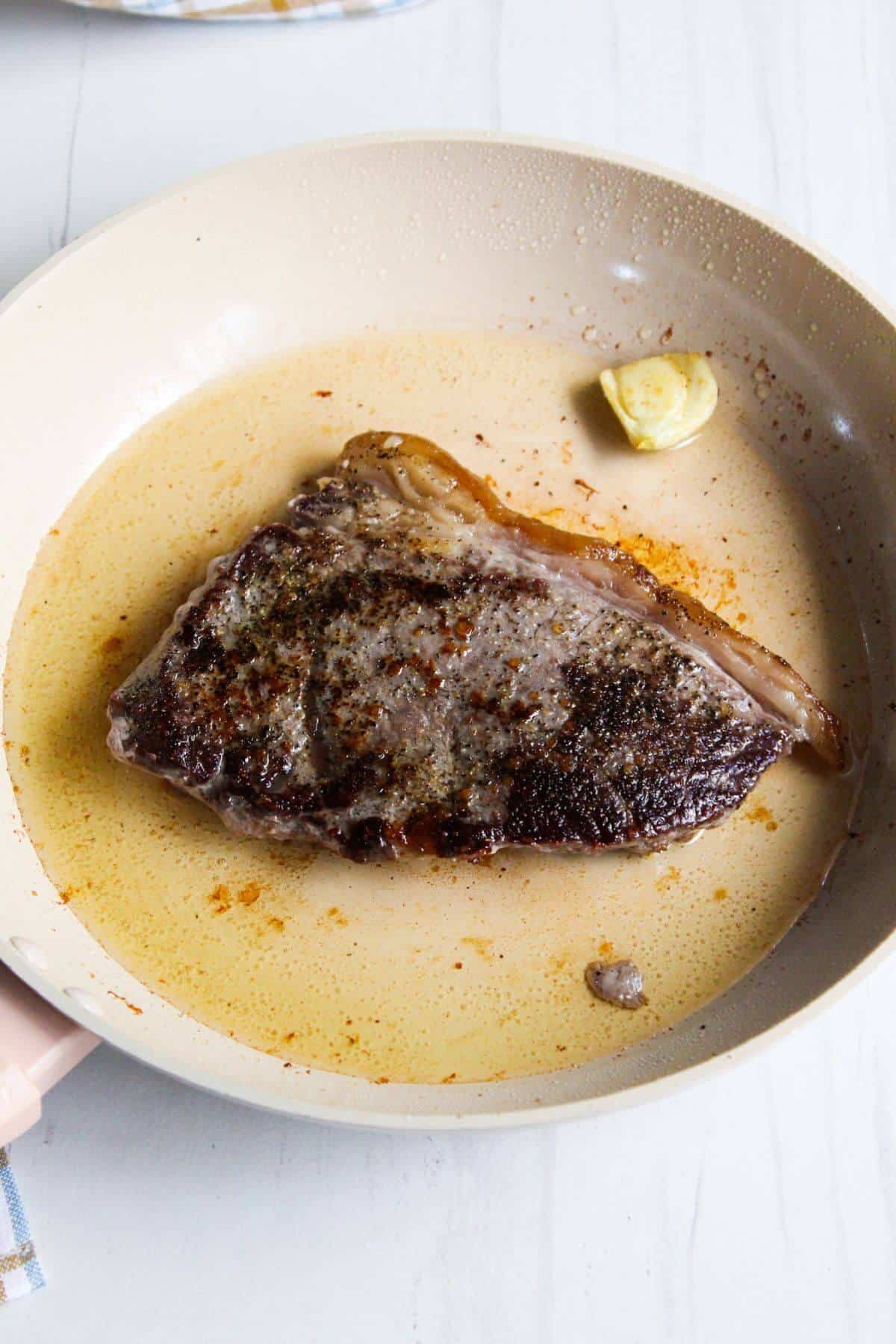 Seared steak in skillet.